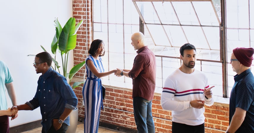 People talking and shaking hands at a contemporary workplace