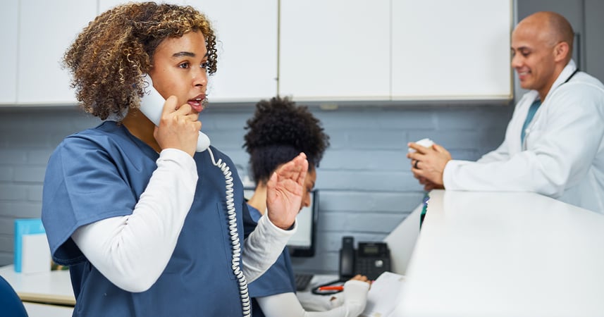 staff on phone at front desk in busy dental office