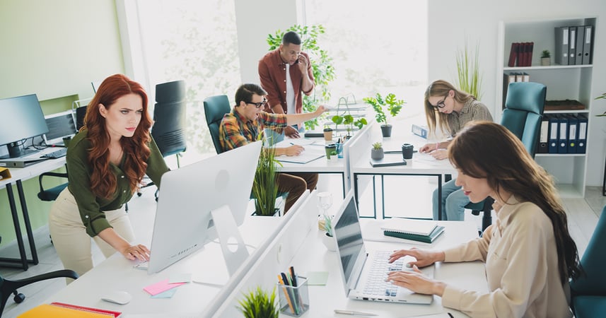Office workers working in an office with an open floor plan. 