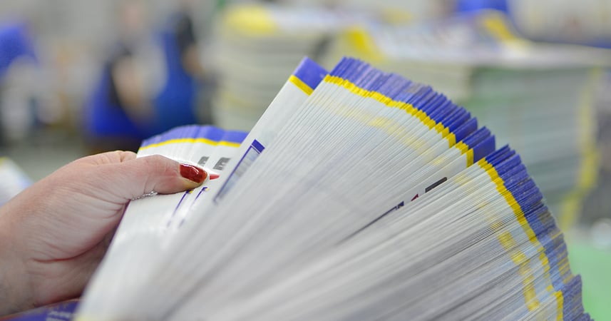 female hand paging through a stack of printed brochures