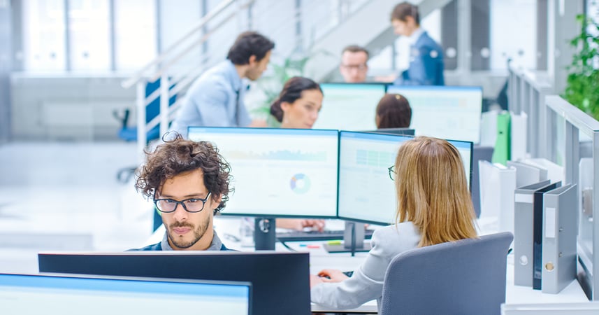 Busy open plan office with people working at desks. 