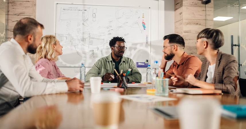 Five co-workers in an office conference room having a meeting