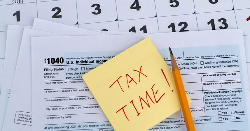 A U.S. 1040 paper tax return shown with a calendar, pencil and yellow 