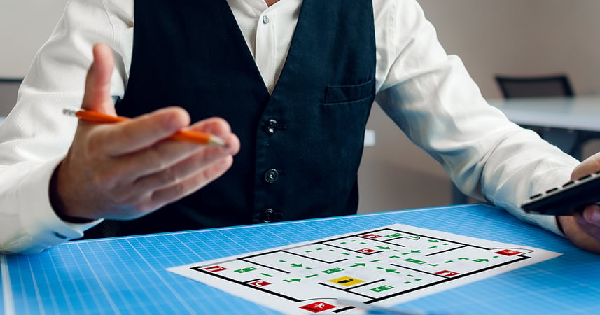 office worker looking at a floor plan while holding a pencil