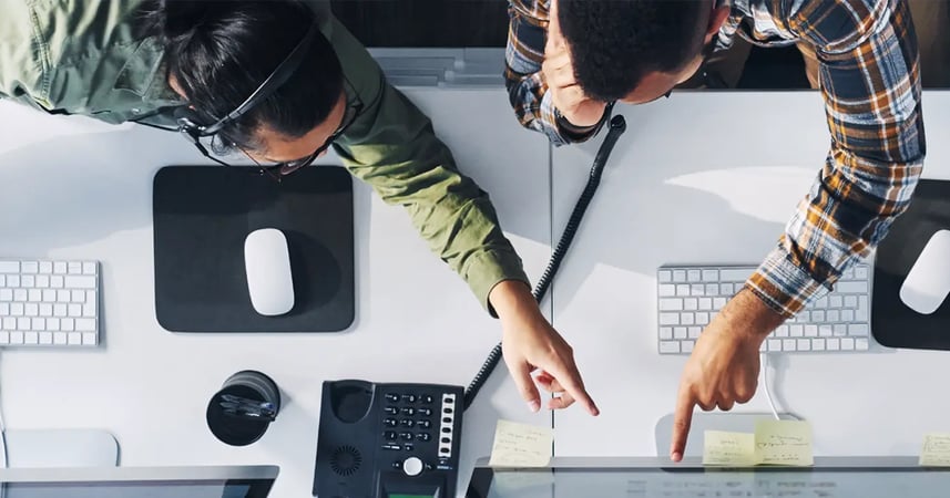 two people working at an office, one is on a phone call