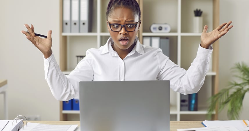 woman with laptop in office surprised at information on screen