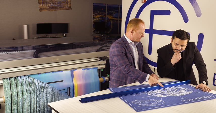 two businessmen reviewing a large printed banner