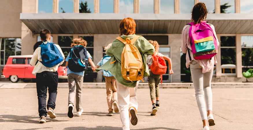 Kids with backpacks headed toward school building
