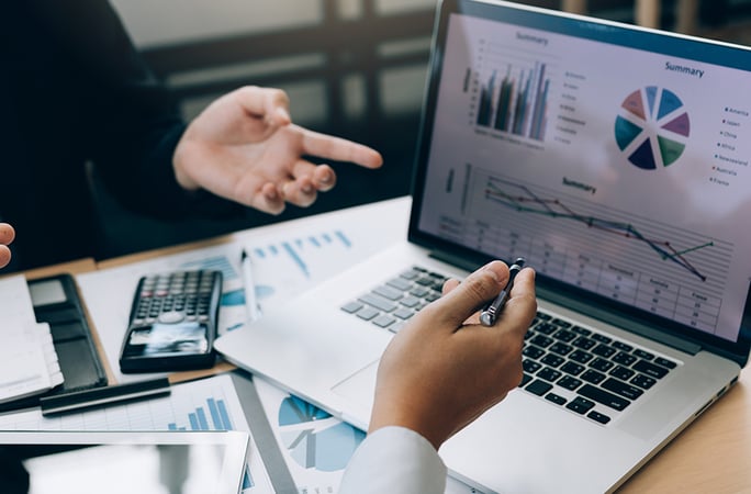 people pointing at laptop with charts