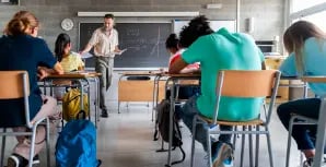 Teacher handing out papers to students in a classroom