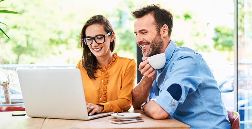 man and woman drinking coffee looking at computer