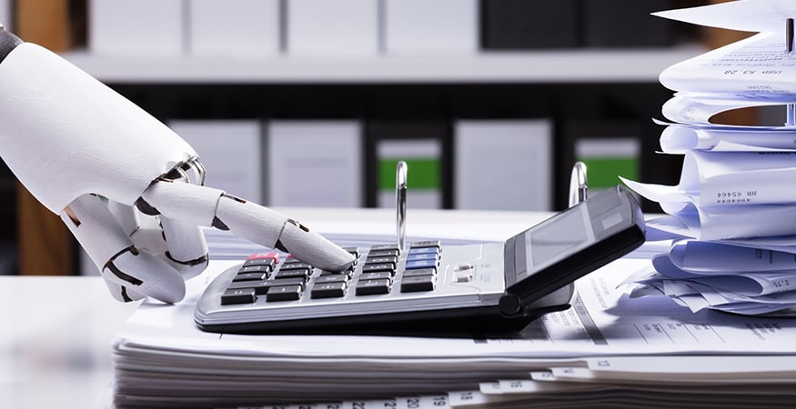 An humanoid robot hand typing on a large calculator.