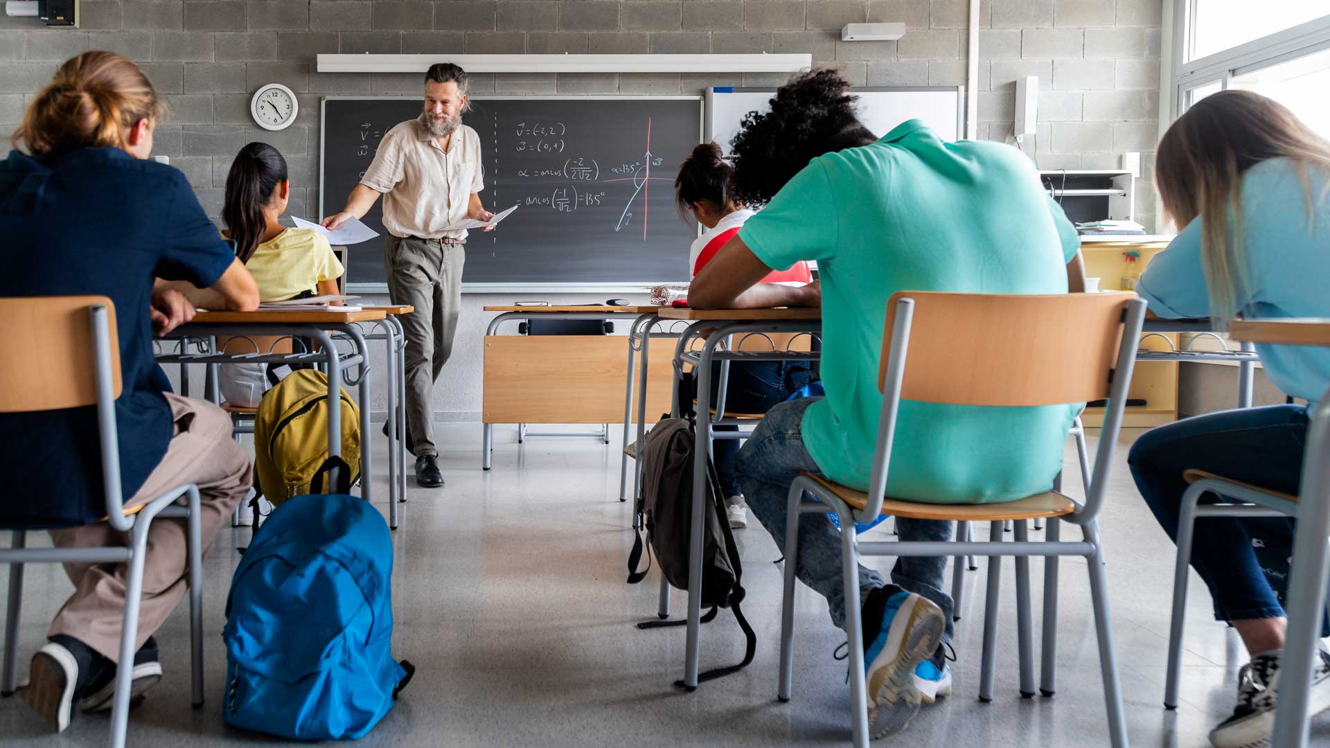 teacher-handing-out-papers-in-school