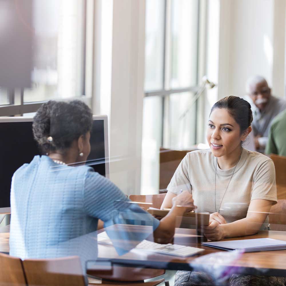 two_women_at_bank_talking_across_desk