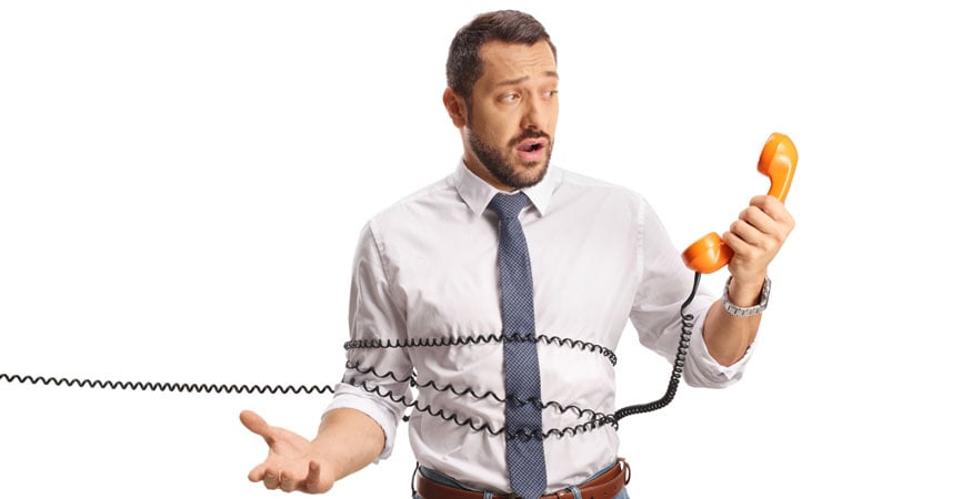 businessman tangled in a phone cord and looking confused