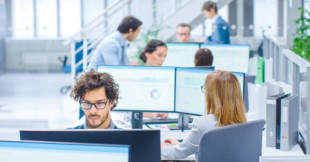 Busy open plan office with people working at desks. 