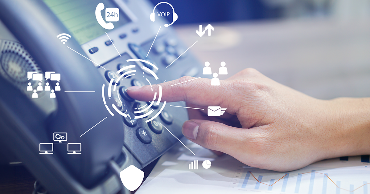 hand of an employee pushing buttons to dial an office phone on a desk