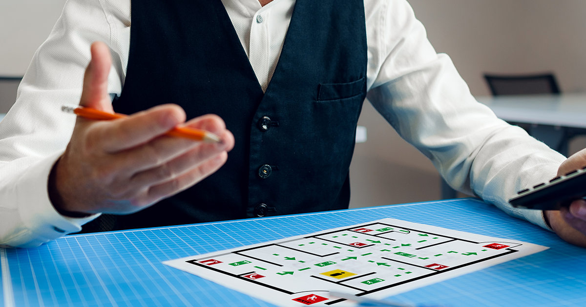 office worker looking at a floor plan while holding a pencil