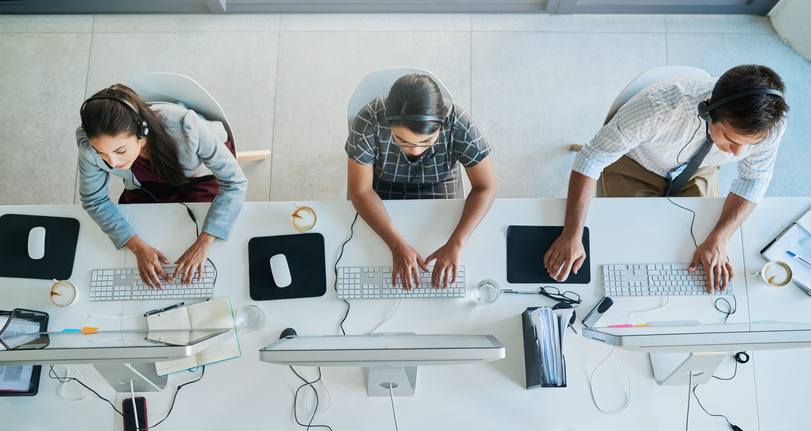 three people working on computers and wearing headsets