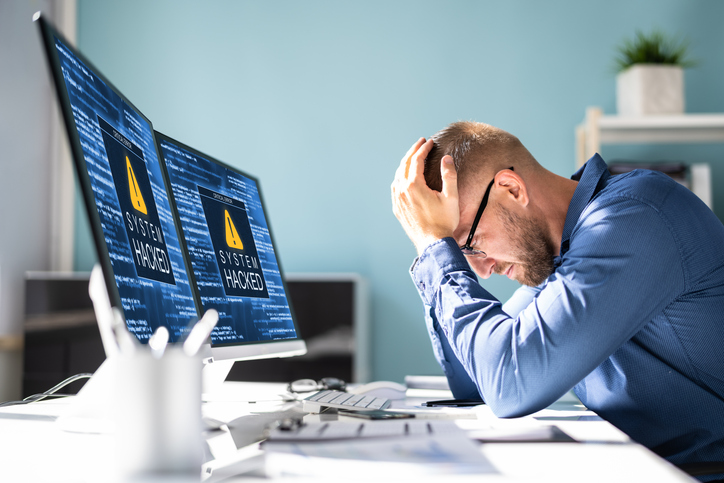 Person sitting at desk with computer saying system hacked