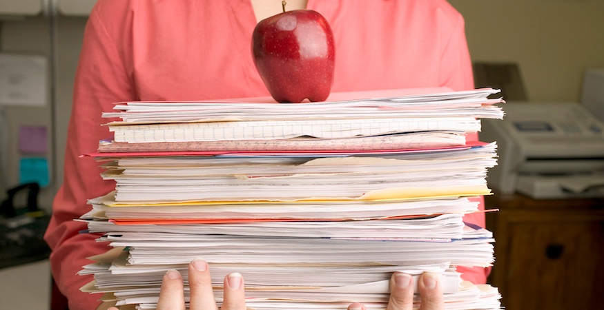 person holding stack of papers and apple